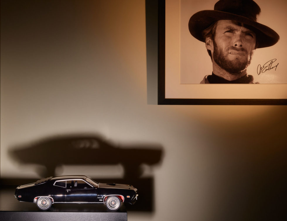Detail of 1960s-themed room at 47 Boutique Hotel with Clint Eastwood photo and Ford Gran Torino model, minimalist and authentic style